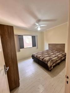 um quarto com uma cama e uma ventoinha de tecto em Apartamento Temporada Guarujá no Guarujá