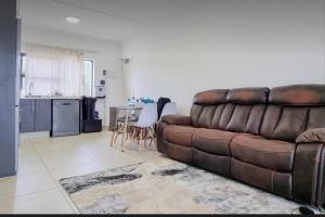 a living room with a brown couch and a kitchen at Leisure apartment in Ballito