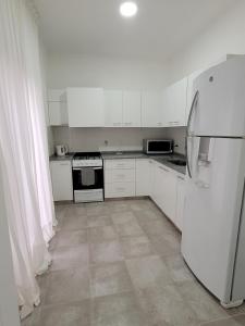 Una cocina con gabinetes blancos y un refrigerador. en Casa Supremo, en Concepción del Uruguay 8 fotos más