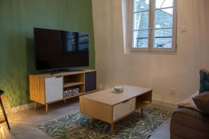 ein Wohnzimmer mit einem Flachbild-TV und einem Couchtisch in der Unterkunft Le Fontaine - Hyper Centre - Vue Cathédrale - Wifi in Mende
