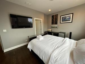 a bedroom with a white bed and a flat screen tv at Wrigley Penthouse with Private Roof Deck and Parking in Chicago