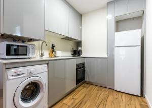 cocina con armarios blancos, lavadora y secadora en Stylish Dúplex - 1 Bd 1Bth- Plaza Castilla, en Madrid