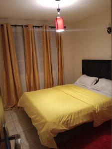 a bedroom with a bed with yellow sheets and curtains at Lux Suites Neema court Apartments in Nairobi