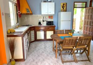 een keuken met een tafel en stoelen en een koelkast bij Gîtes Soleil étoilé - Piscine - Jardin fleuri - Terrasse in Anse-Bertrand