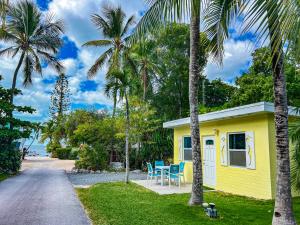 una casa amarilla con sillas azules y palmeras en Sunset Cove Beach Resort, en Cayo Largo