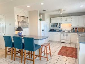 ドーフィン・アイランドにある051 Topsailの白いキャビネットと青い椅子が備わる島のキッチン