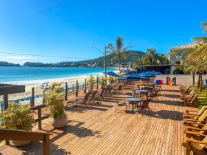 una terraza de madera con sillas y mesas en la playa en Pousada Vila do Coral, en Bombinhas