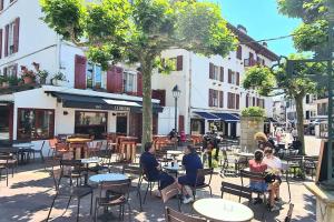 a group of people sitting at tables in a street at Appartement rue Gambetta, plage à 2 min in Saint-Jean-de-Luz