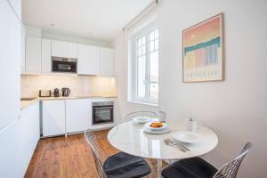 a white kitchen with a white table and chairs at Appartement rue Gambetta, plage à 2 min in Saint-Jean-de-Luz