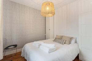 a bedroom with a white bed with a chandelier at Appartement rue Gambetta, plage à 2 min in Saint-Jean-de-Luz