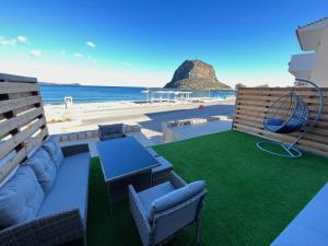 une terrasse avec un canapé et une balançoire sur la plage dans l'établissement Seafront Luxury Suite with Jacuzzi & Sauna, à Monemvasia