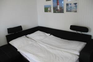 uma cama com lençóis brancos e duas cadeiras num quarto em Fewo Nordseestraße 5 em Büsum