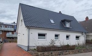 a white house with a black roof at Fewo Voßeler in Büsum