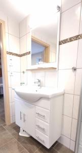 ein weißes Badezimmer mit einem Waschbecken und einem Spiegel in der Unterkunft Fewo Voßeler in Büsum