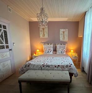 um quarto com uma cama e um lustre em Chambre d'hôtes - La Pinstrie 