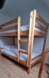 ein Etagenbett aus Holz in einem Zimmer mit einem Stuhl in der Unterkunft Fewo Voßeler in Büsum