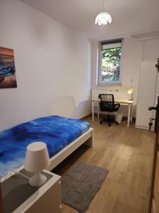 um quarto com uma cama azul e uma secretária em Przytulne pokoje u Julii em Rzeszów