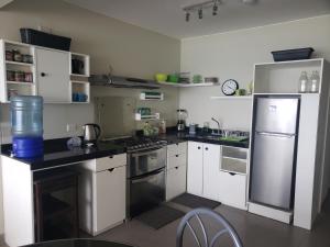 uma cozinha com armários brancos e electrodomésticos de aço inoxidável em Playa el Silencio lindo apartamento! no mascotas deposito para reservar em Bombiso