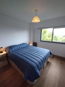a large blue bed in a room with a window at MIRADOR DEL CENTRO BARILOCHE in San Carlos de Bariloche
