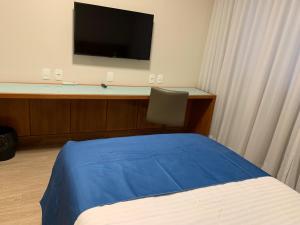 a bedroom with a bed and a desk with a television at Casa do Professor Visitante Unicamp in Campinas
