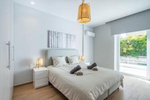 a white bedroom with a large bed and a window at Glyfada Glamorous in Athens