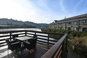a table and chairs on a deck next to a river at Edgewater Inn and Suites in Coos Bay