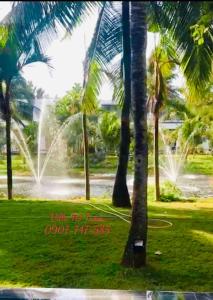 um parque com palmeiras e uma fonte de água em Biệt thự 5PN Resort Sanctuary HỒ Tràm ll Bãi biển riêng ll hồ bơi BBQ em Xuyên Mộc