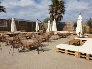 een patio met tafels en stoelen en witte parasols bij Mobile-home les pieds dans l'eau in Palavas-les-Flots