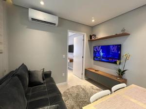 a living room with a couch and a flat screen tv at Lindo Apto Mobiliado próximo a praia em Santos in Santos