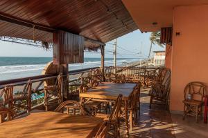 San Alejo Zero في San Jacinto: مطعم به طاولات وكراسي والشاطئ