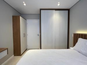 a bedroom with a large white bed and a closet at Lindo Apto Mobiliado próximo a praia em Santos in Santos
