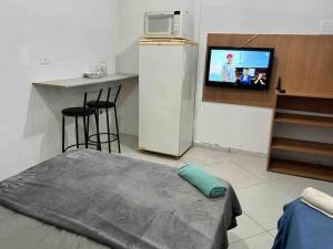 um quarto com uma cama e uma cozinha com uma televisão em Studio Aconchegante Ao lado Expo Center Norte SP em São Paulo