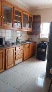 uma cozinha com armários de madeira e um fogão preto em Precious Estates Pearls em Zeerust