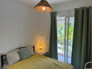a bedroom with a bed with green curtains and a window at Oasis de Paix près de la plage in Flic-en-Flac