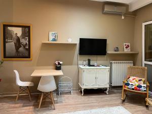 un soggiorno con TV, tavolo e sedie di Downtown Zemun Studio Apartment a Belgrado