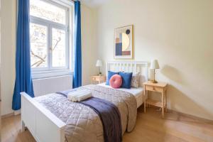 Exclusive & Spacious Central Residence w/ 4BEDRM 2BATHRM في بودابست: غرفة نوم بسرير والستائر الزرقاء ونافذة