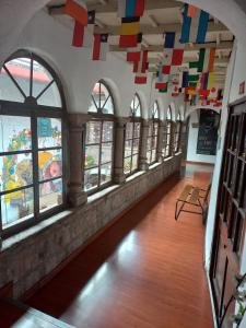 una habitación con ventanas y banderas coloridas colgando del techo en Pirwa Backpackers Colonial en Cusco