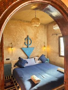 a bedroom with a blue bed with a blue anchor on the wall at Camels House in Merzouga