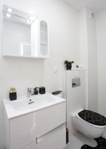 uma casa de banho branca com um lavatório e um WC em Apartament Modern Ivory Pipera em Voluntari