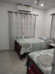 een kamer met 2 bedden, gordijnen en een ventilator bij Espectacular cabaña en Coveñas - Sucre, Frente al mar!!! in Coveñas