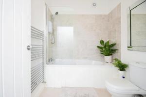 a white bathroom with a tub and a toilet at Bluebell Cottage Mumbles - Sea Views in The Mumbles