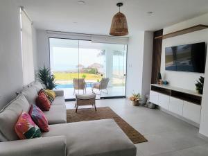 uma sala de estar com um sofá e uma televisão em HERMOSA CASA CON PISCINA FRENTE AL MAR - PRIMERA FILA em Chincha Baja