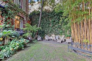 a garden with a bench and a wall with vines at Villa Boileau - Welkeys in Paris +17 photos