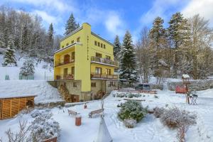 un edificio amarillo con nieve en el suelo en Willa Antidotum en Krynica Zdrój