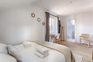 a white bedroom with a bed with towels on it at Magnifique Villa Anatole France en plein coeur de Paris - 11P in Saint-Denis