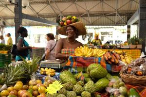 una mujer parada en un mercado con frutas y hortalizas en Studio climatisé dans Résidence avec piscine, à proximité de la mer en La Trinité