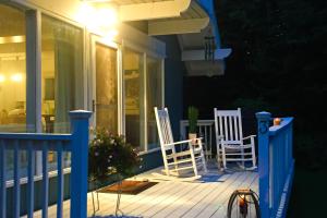 two white chairs sitting on a porch at night at Buzz's Place in Barnumville