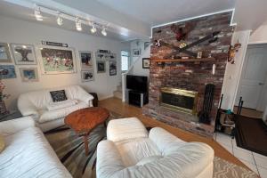 a living room with white furniture and a brick fireplace at Buzz's Place in Barnumville