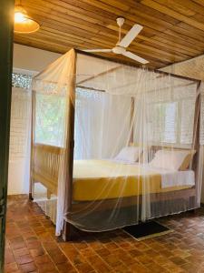 a canopy bed in a room with a ceiling at Whispering House in Tangalle