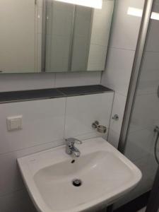 ein Badezimmer mit einem weißen Waschbecken und einem Spiegel in der Unterkunft 2 Zimmer Ferienwohnung in Sellin auf Rügen - direkt an der Seeparkpromenade in Ostseebad Sellin